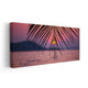 Beach wall art for living room featuring a dreamy ocean sunset framed by palm leaves in the foreground.