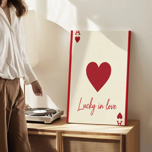 Canvas wall art print with a centered heart, red 'A' letters, and the phrase 'Lucky in love' in a playful, romantic tone.