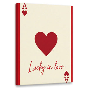 Minimalist canvas wall art featuring a bold red heart, stylized playing card elements, and the phrase 'Lucky in love' in red text.