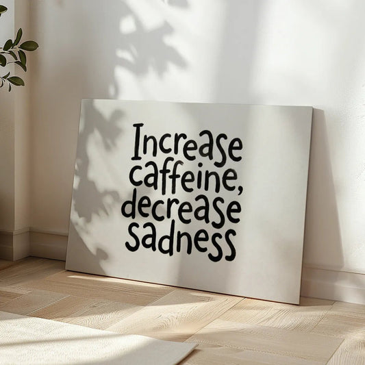 Minimalist canvas wall art with centered black text reading 'Increase caffeine, decrease sadness' on a plain white backdrop