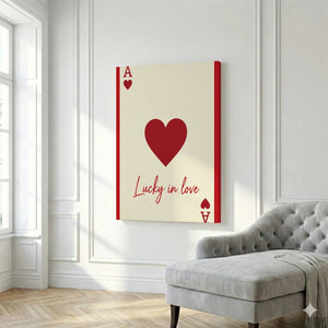 Graphic canvas wall art with a large central heart, cream background, and symmetrical red symbols including 'A' and a heart-shaped spade.