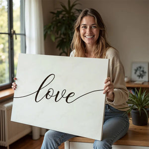 Simple canvas wall decor with black cursive lettering spelling 'love' on a neutral white canvas.