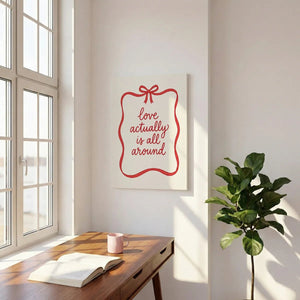 Canvas print showcasing smooth red script reading 'love actually is all around' inside a playful ribbon frame