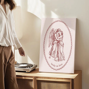 Decorative canvas print with a delicate line drawing of two entwined figures, framed in an oval and captioned with 'lucky in love'.