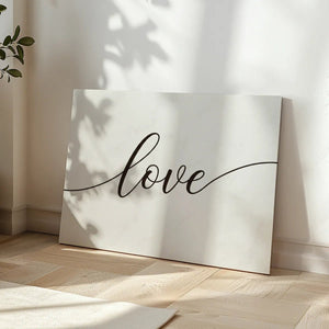 Minimalist canvas wall art with centered cursive 'love' text in black on a white backdrop, suited for romantic spaces.