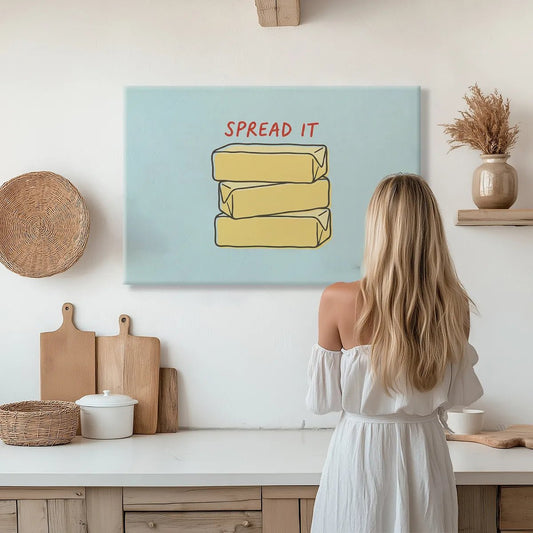 Typography canvas wall art with playful red lettering reading 'SPREAD IT' above cartoon-style butter blocks