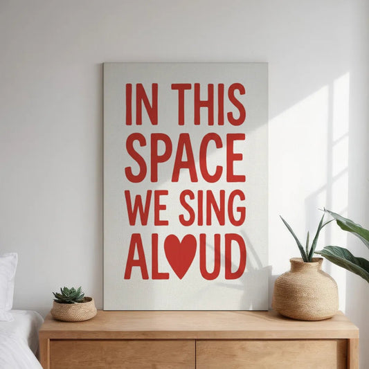 Minimalist canvas wall art with centered red typography on white, reading 'IN THIS SPACE WE SING ALOUD' with a heart in place of the 'O'.