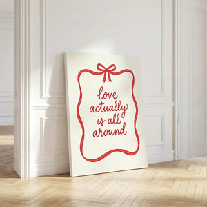 Canvas wall decor with centered red cursive typography enclosed by a single red ribbon and bow on a clean white backdrop
