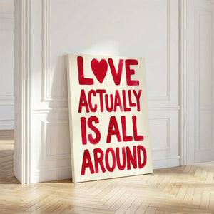 Bold canvas print showcasing the phrase 'LOVE ACTUALLY IS ALL AROUND' in uppercase red letters with a heart replacing the 'O'.