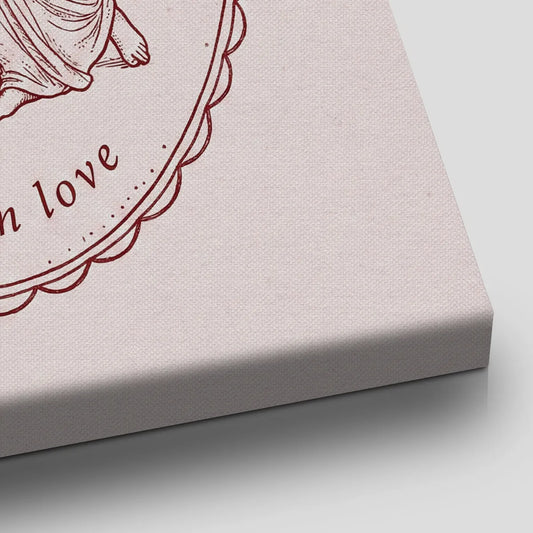 Romantic canvas wall art showing a winged figure embracing a draped partner within a detailed oval border and muted burgundy tones.