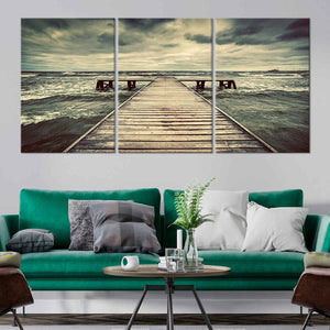 Beach scene canvas art featuring a weathered wooden pier extending into rough waters.
