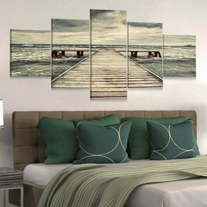 Coastal farmhouse wall decor showcasing an old pier under dark, moody clouds.