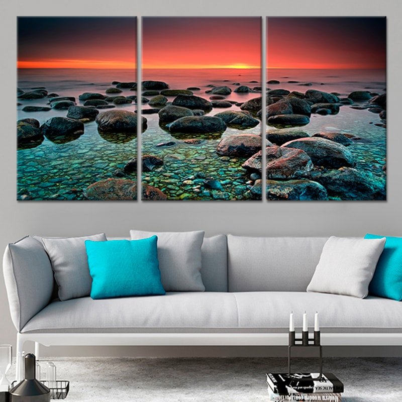 Abstract beach rock formations with soft sea waves under a fiery sky.